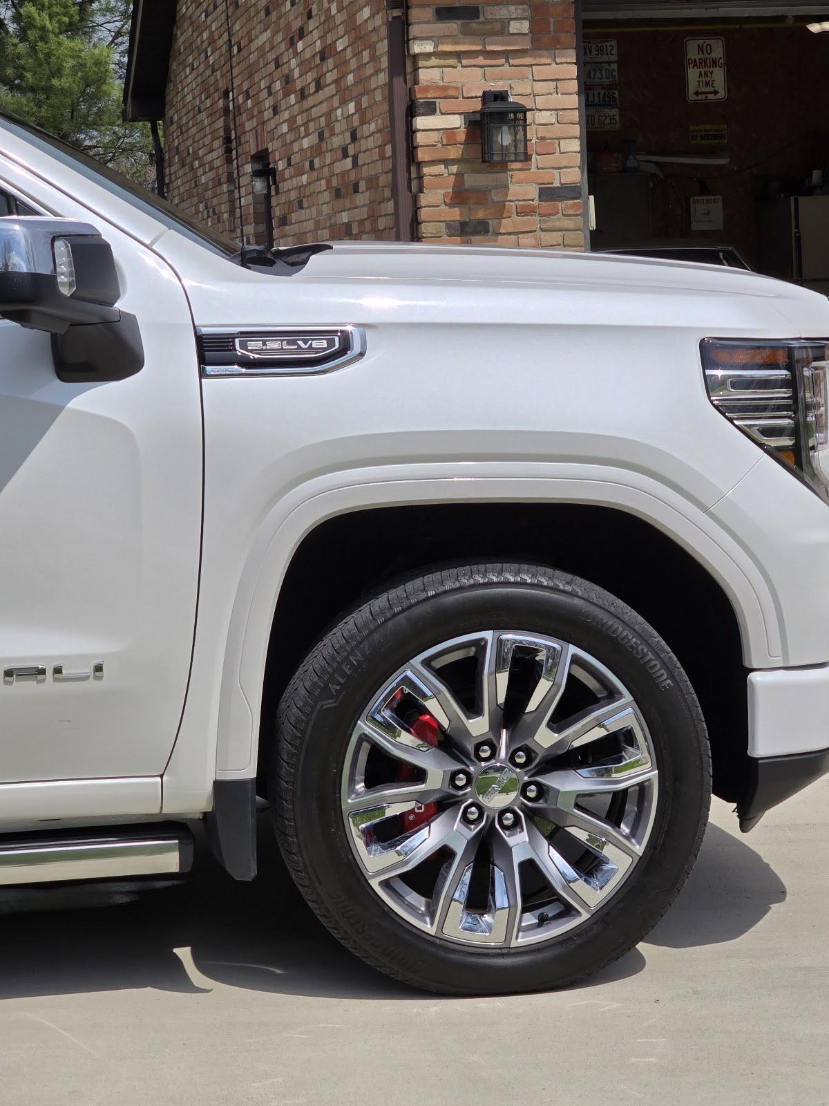 Close-up of a repaired white GMC Denali fender and wheel