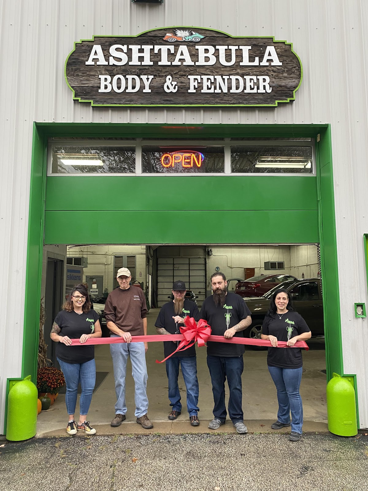 The Ashtabula Body & Fender team cutting the ribbon at the shop's open garage door